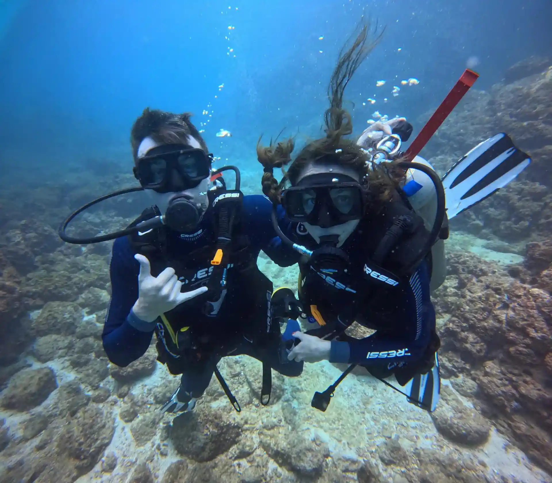 Two divers surrounded by a rock formation under the waters of the Pacific Ocean after completing a PADI certification course in Costa Rica
