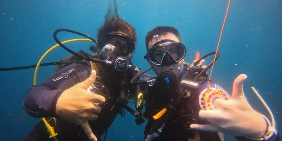 Underwater photo of PADI instructor Josue and a newly certified diver flashing hang ten signs off Playa Potrero, Costa Rica.
