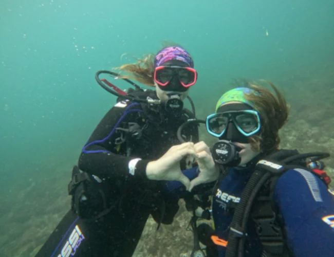 Two PADI graduates making a heart sign underwater in Costa Rica