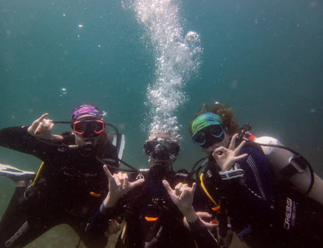 Three scuba divers celebrating underwater in Guanacaste, Costa Rica