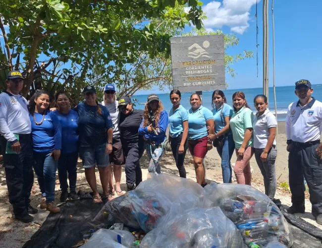 Group of volunteers and local police with collected trash bags at a beach cleanup in Playa Potrero, Costa Rica