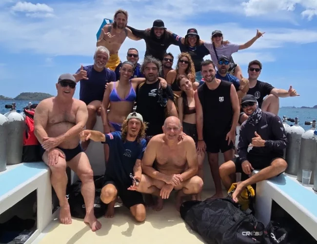 Group of scuba divers posing with tanks and gear on a dive boat off Playa Potrero, Costa Rica