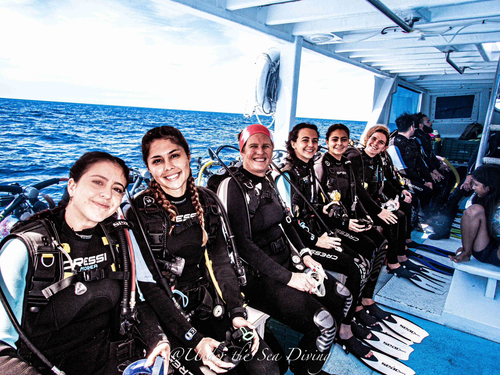Group of smiling scuba students in dive gear aboard the boat before a course dive in Guanacaste, Costa Rica