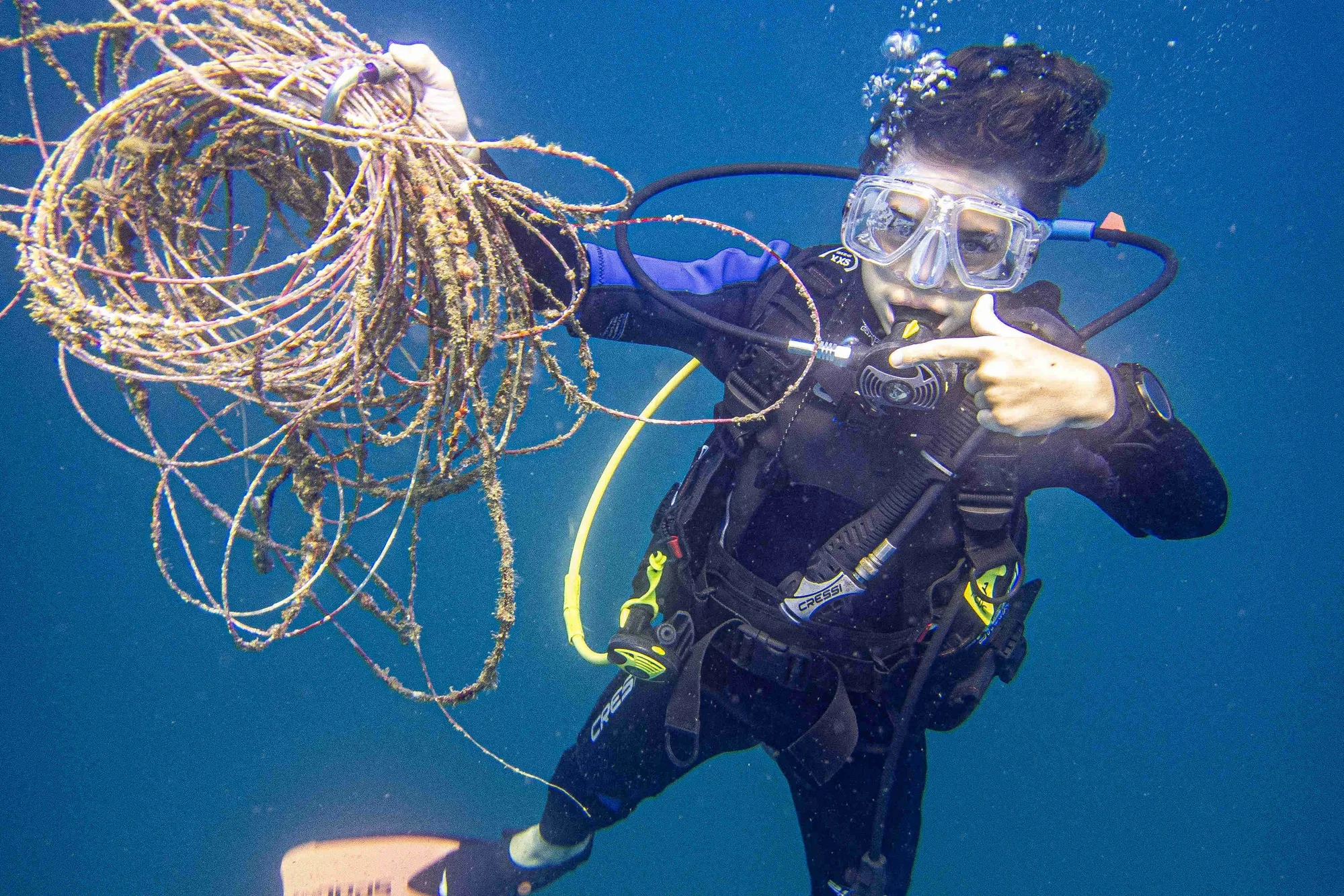 Scuba diver removing tangled ghost fishing line during a marine conservation dive in Guanacaste, Costa Rica