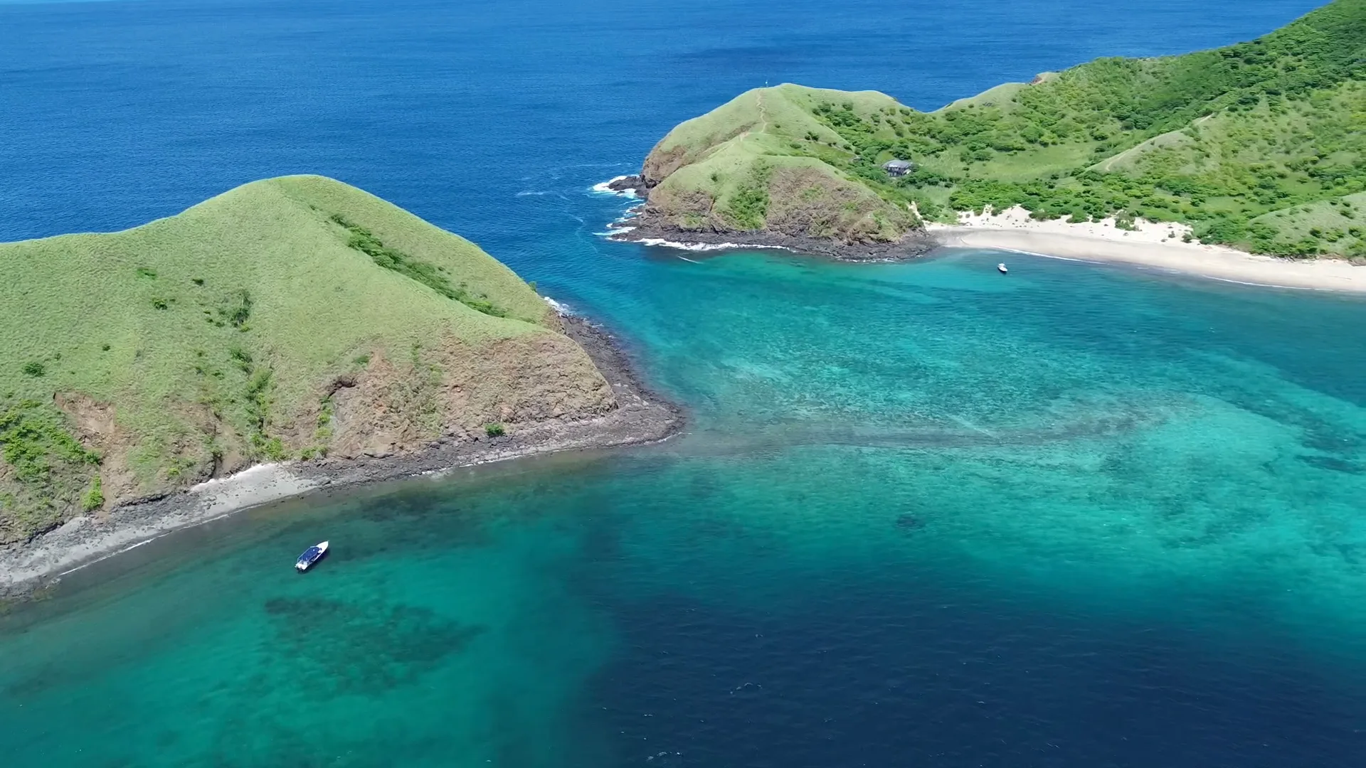 Aerial view of the Guanacaste coastline with turquoise reef waters and a dive boat near Playa Potrero, Costa Rica