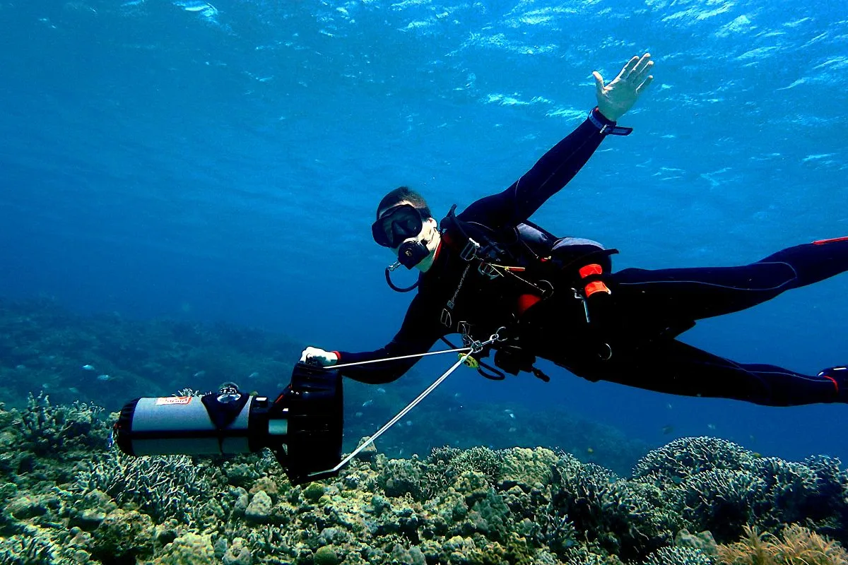 Technical diver gliding over a coral reef with a diver propulsion vehicle (DPV) in Guanacaste, Costa Rica